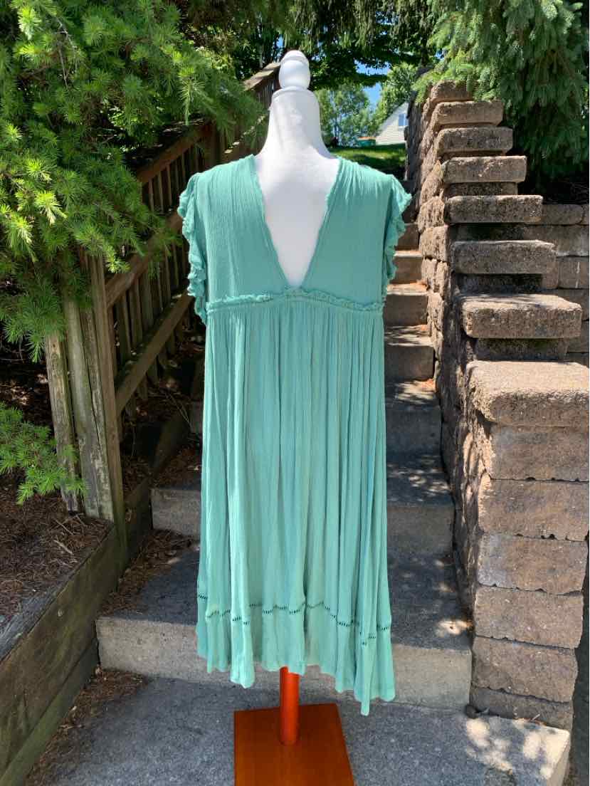 Light teal sleeveless dress with deep V-neck and gathered waist, lightweight fabric with ruffled hem.