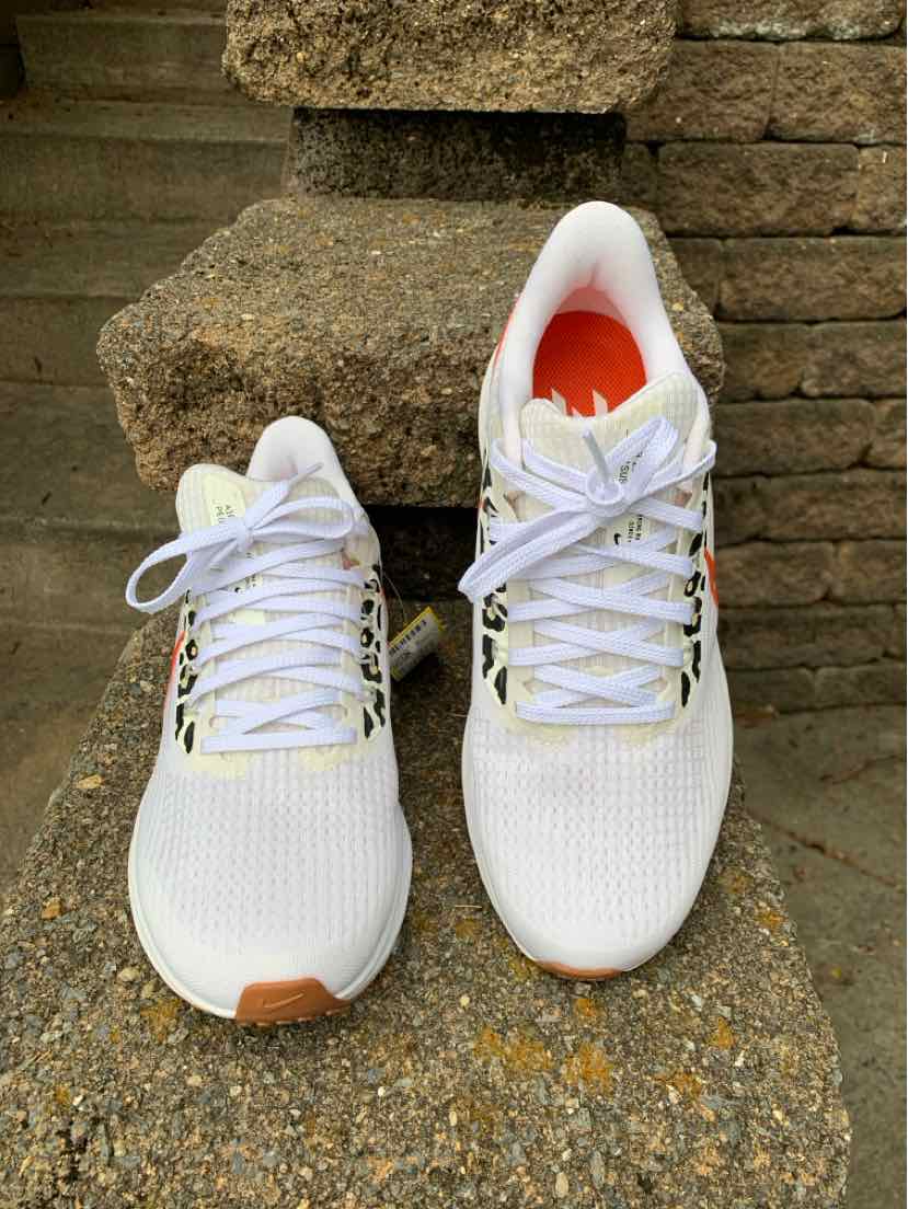 White Nike women’s sneakers with mesh upper, white laces, and orange insoles, size 8.5.