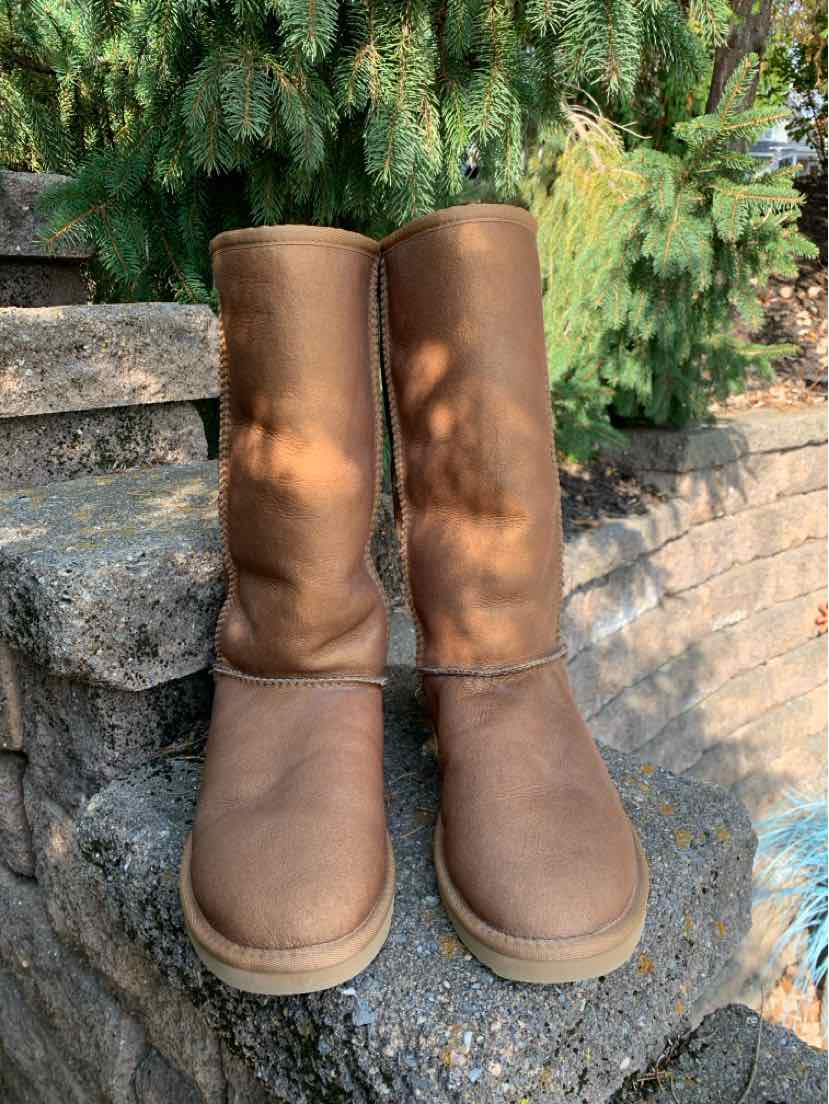 Pair of brown suede UGG boots with tall shafts, rounded toes, and thick rubber soles.