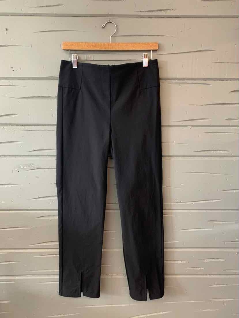 Black Athleta women's pants size 10 with front seam and ankle slits, hanging on wooden hanger.