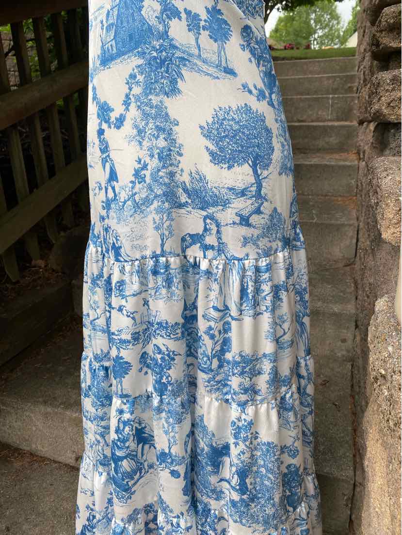 White maxi skirt with blue floral and scenic toile print, gathered tier design, lightweight fabric.