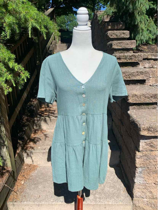 Light green short-sleeve tiered dress with V-neck and front buttons on mannequin outdoors.