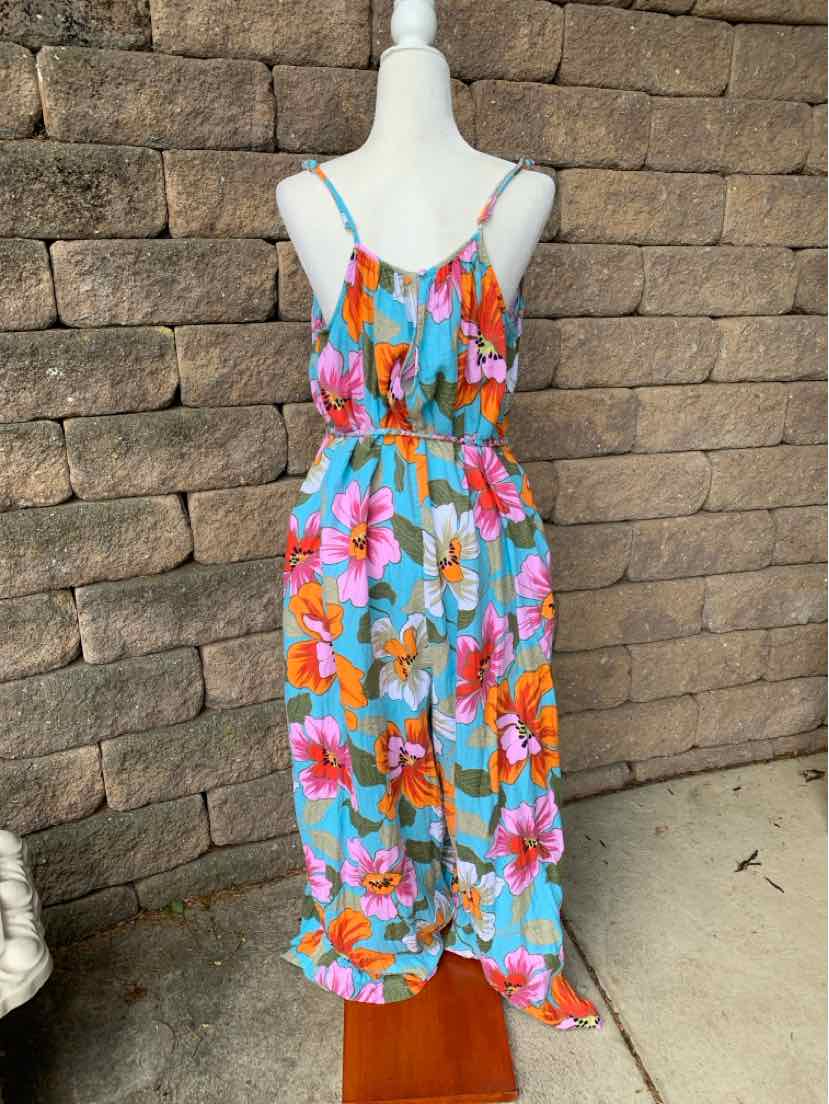Sleeveless tropical-print jumpsuit with blue base, orange and pink flowers, adjustable straps, elastic waist, and wide legs.