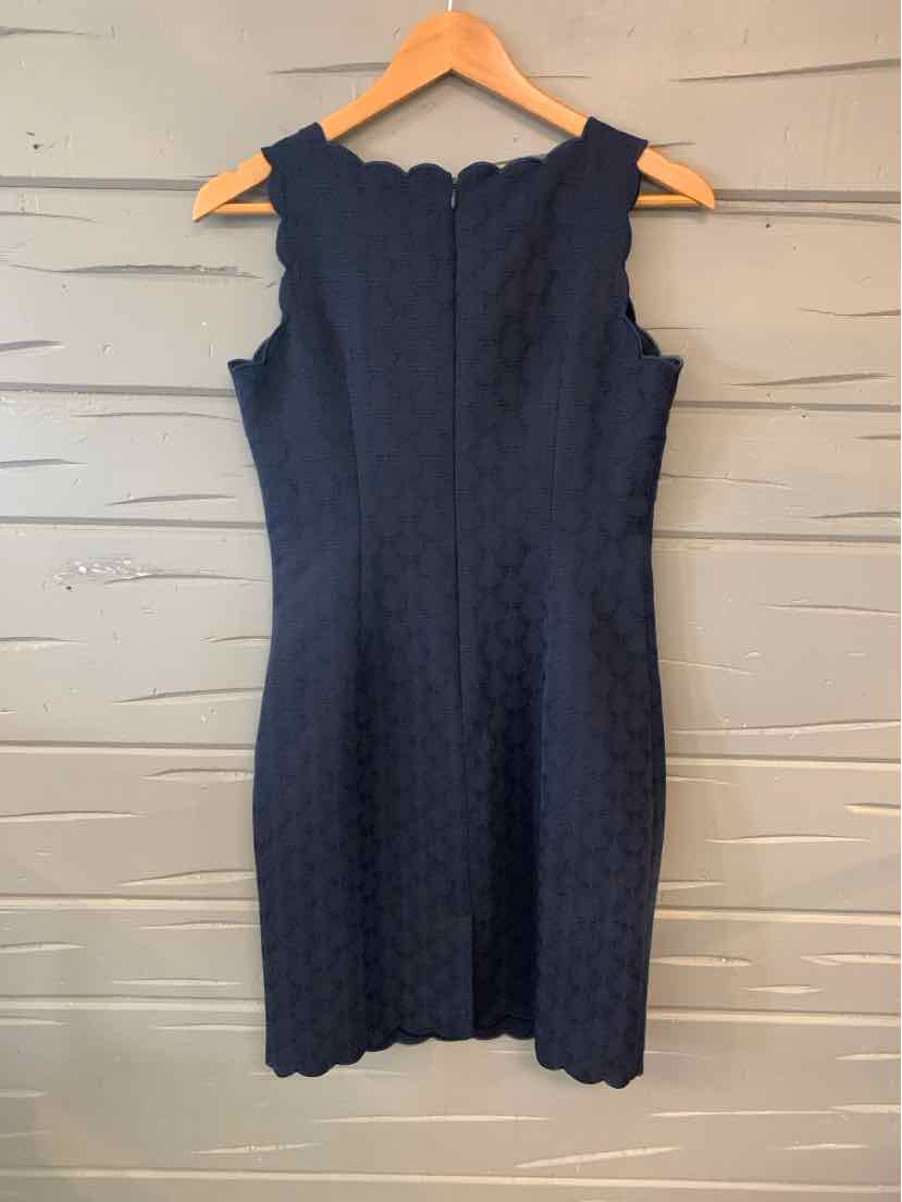 Navy blue sleeveless textured dress with scalloped edges on neckline and hem, fitted silhouette.