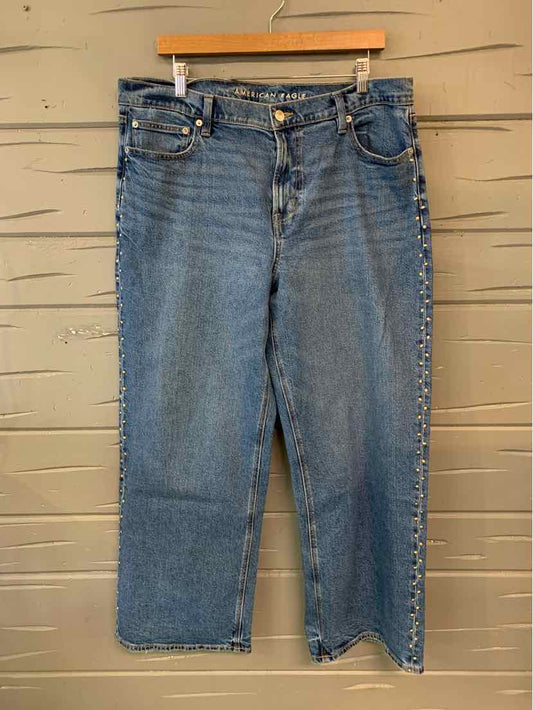 Blue denim jeans in size 14 with classic five-pocket design and button closure hanging on wooden hanger.