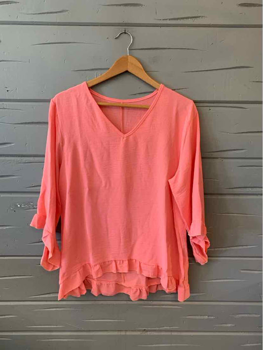 Loose-fit melon-colored blouse with V-neck and rolled 3/4 sleeves on wooden hanger.