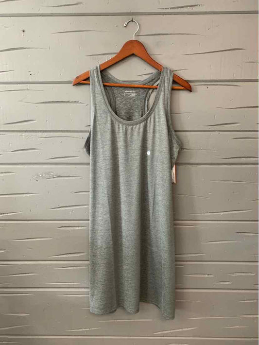 Light gray sleeveless scoop neck dress with relaxed fit hanging on wooden hanger against light wall.