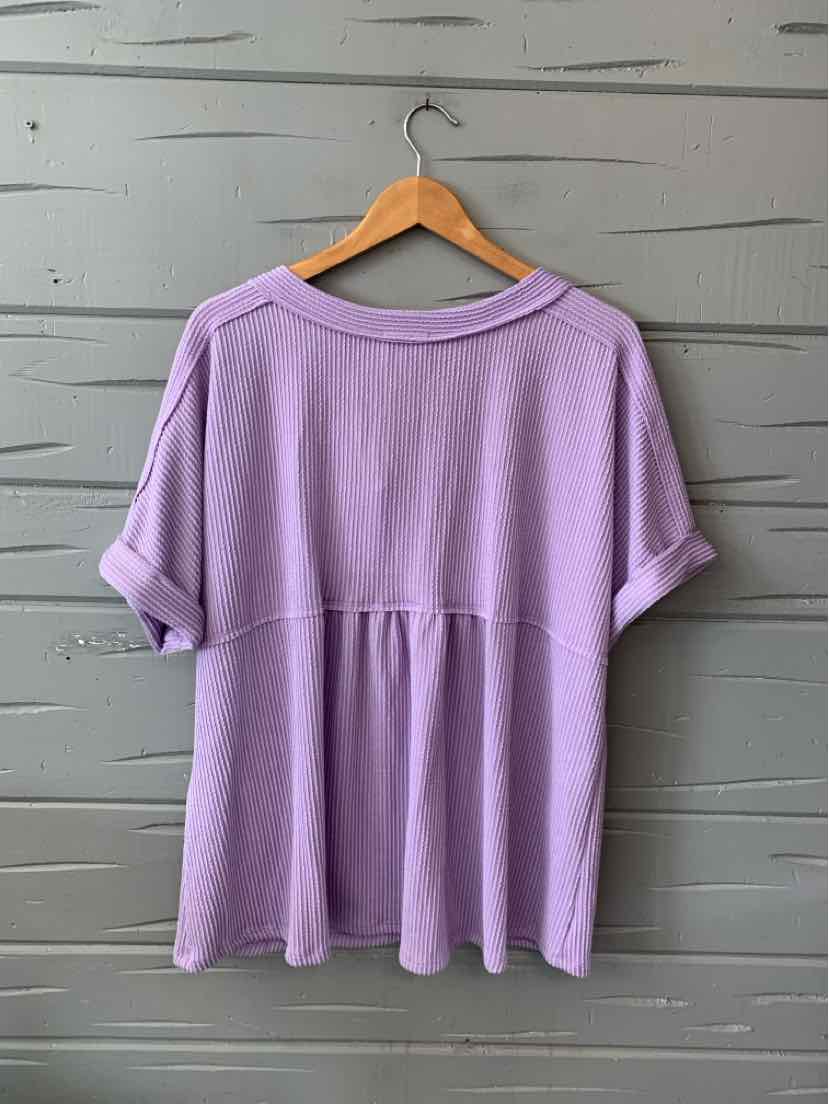 Lavender purple short-sleeve top with gathered back seam and rolled cuffs on wooden hanger.