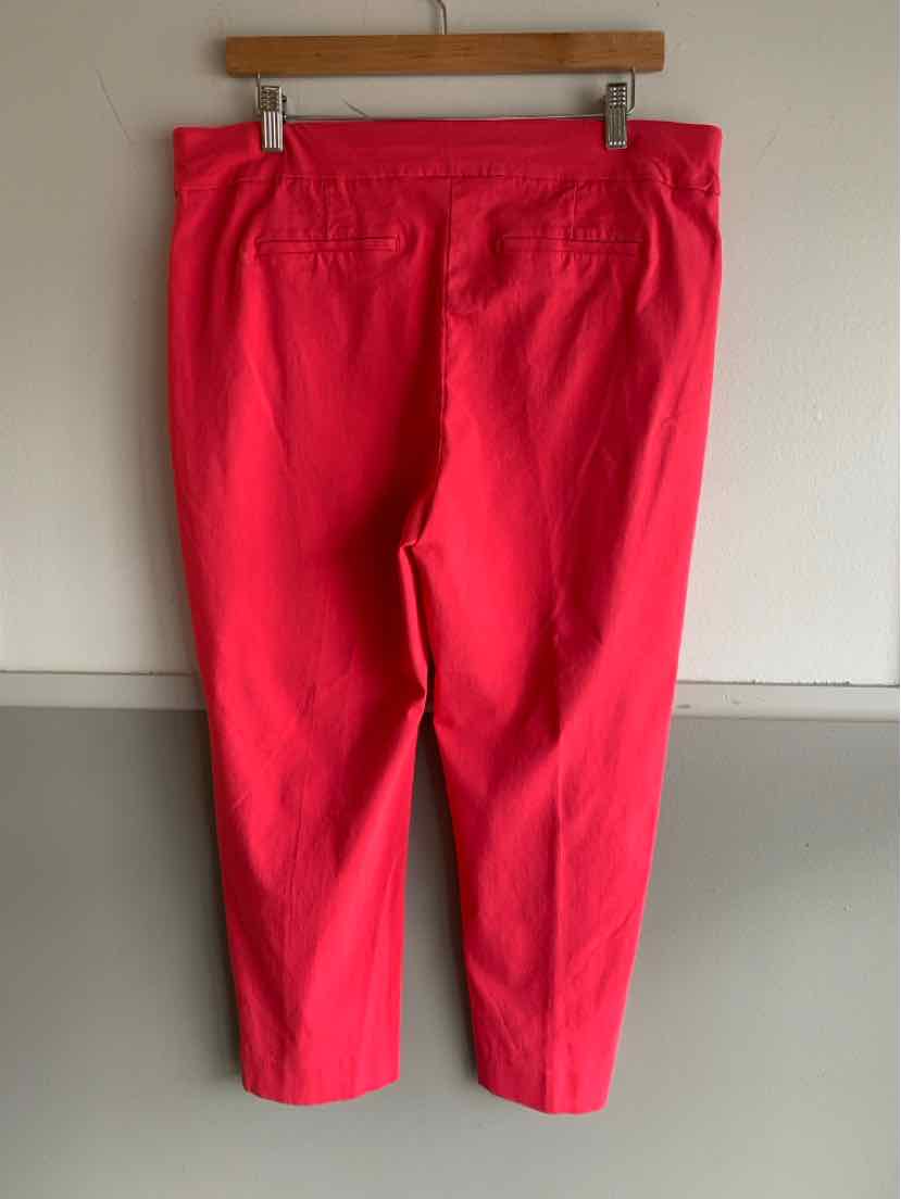 Bright red mid-rise pants with an elastic waistband and cropped legs hanging on a wood hanger.
