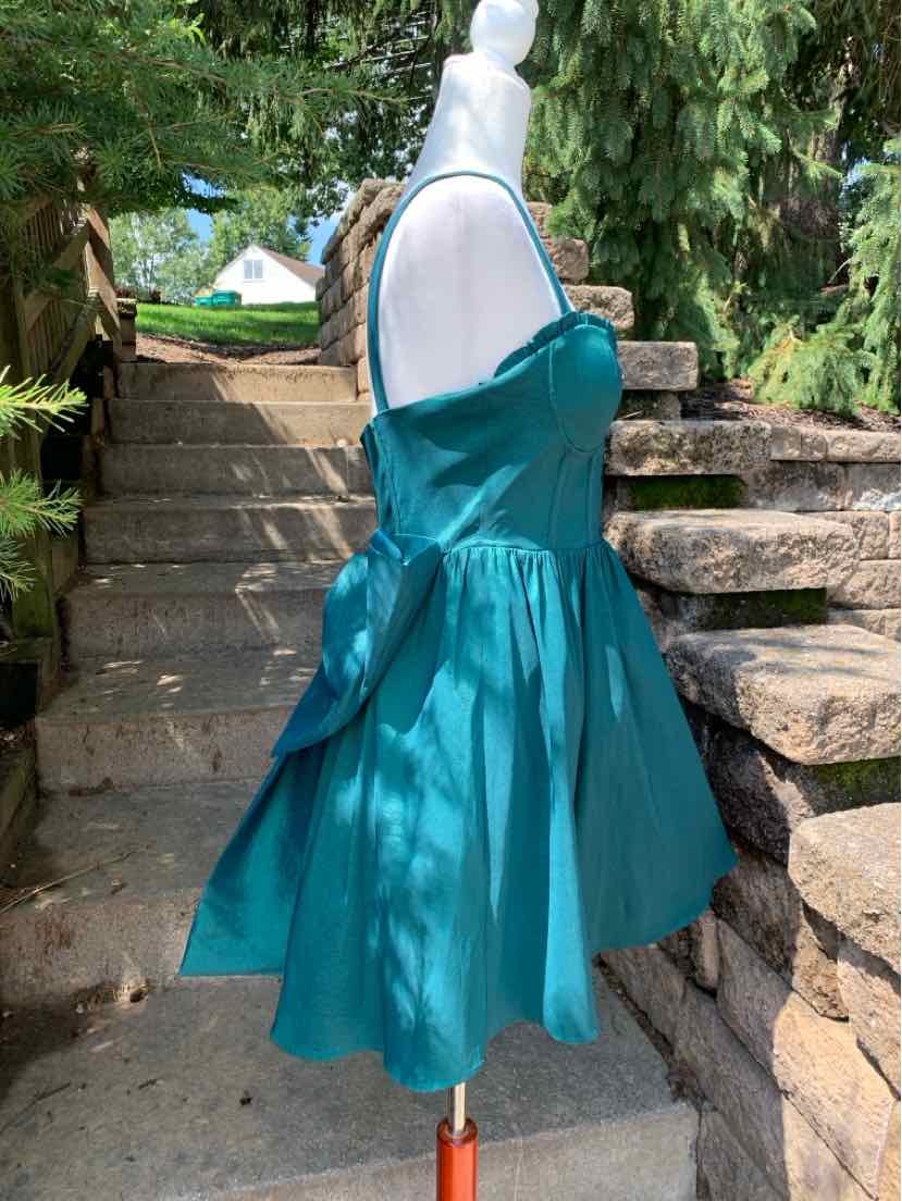 Teal sleeveless mini dress with fitted bodice, square neckline, and full gathered skirt.