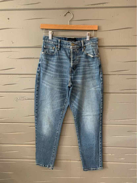 Blue high-waist Lucky Brand denim jeans with a tapered leg and frayed hems hanging on wooden hanger.