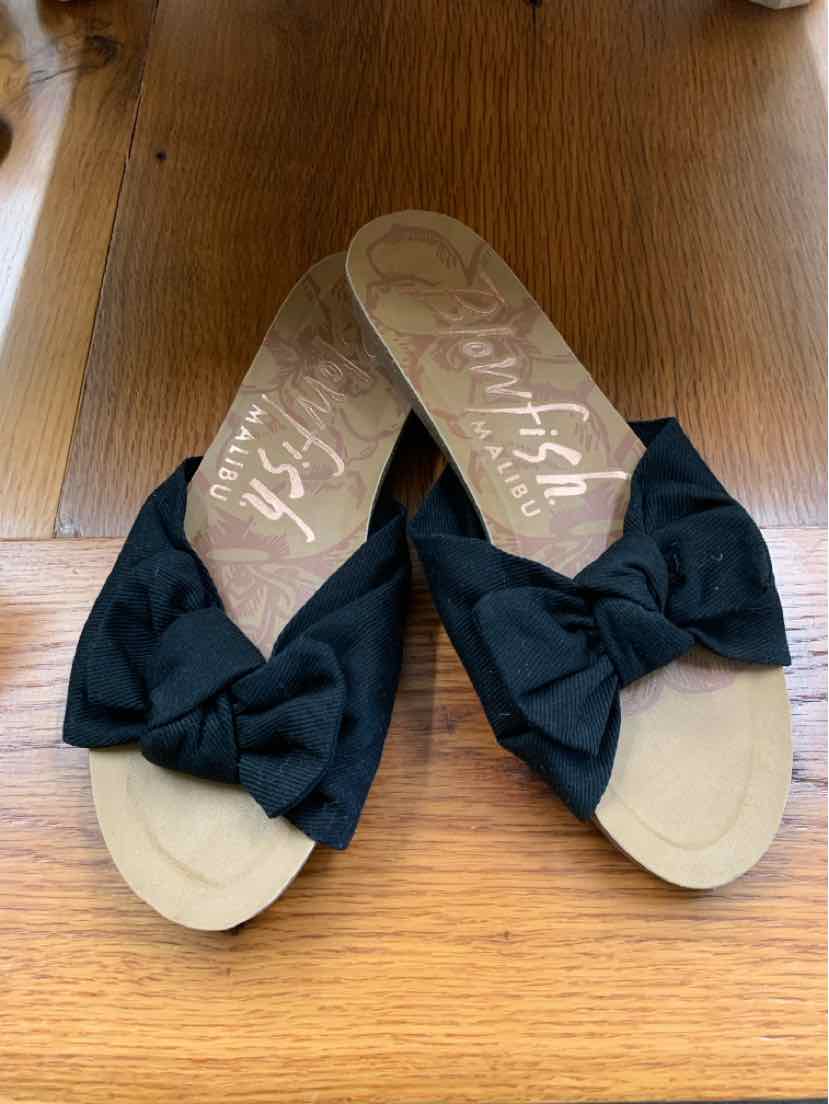 Black fabric bow slide sandals with tan soles and flat heels, size 7.