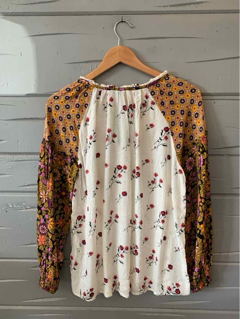 Long-sleeve floral top with white front, mustard yellow floral raglan sleeves, and round neckline.