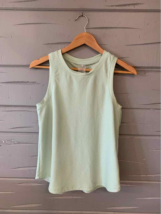 Light green sleeveless tank top with round neckline on wooden hanger against gray wood panel background.