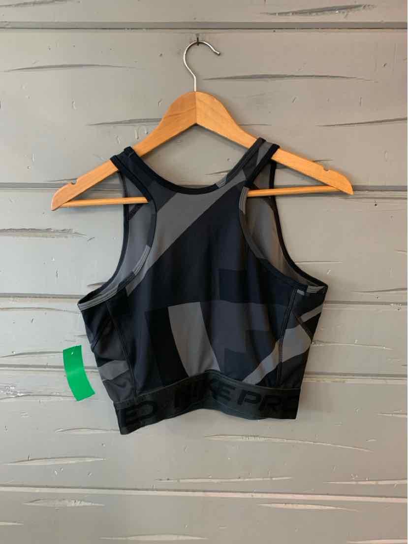 Black Nike sports bra with color block design and racerback straps hanging on wooden hanger.