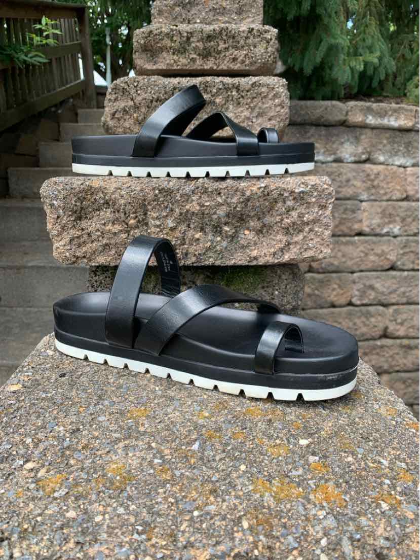 Black slide sandals with crisscross straps, thick white platform sole, size 9.