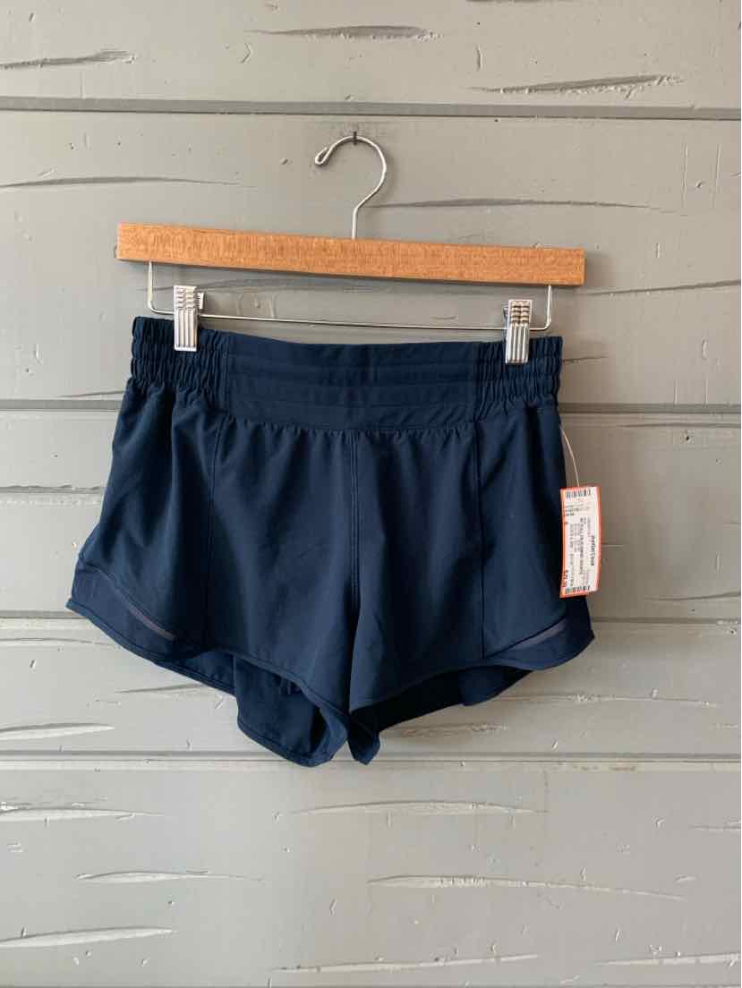 Navy blue athletic shorts with elastic waistband and curved hem, hanging on wooden hanger.