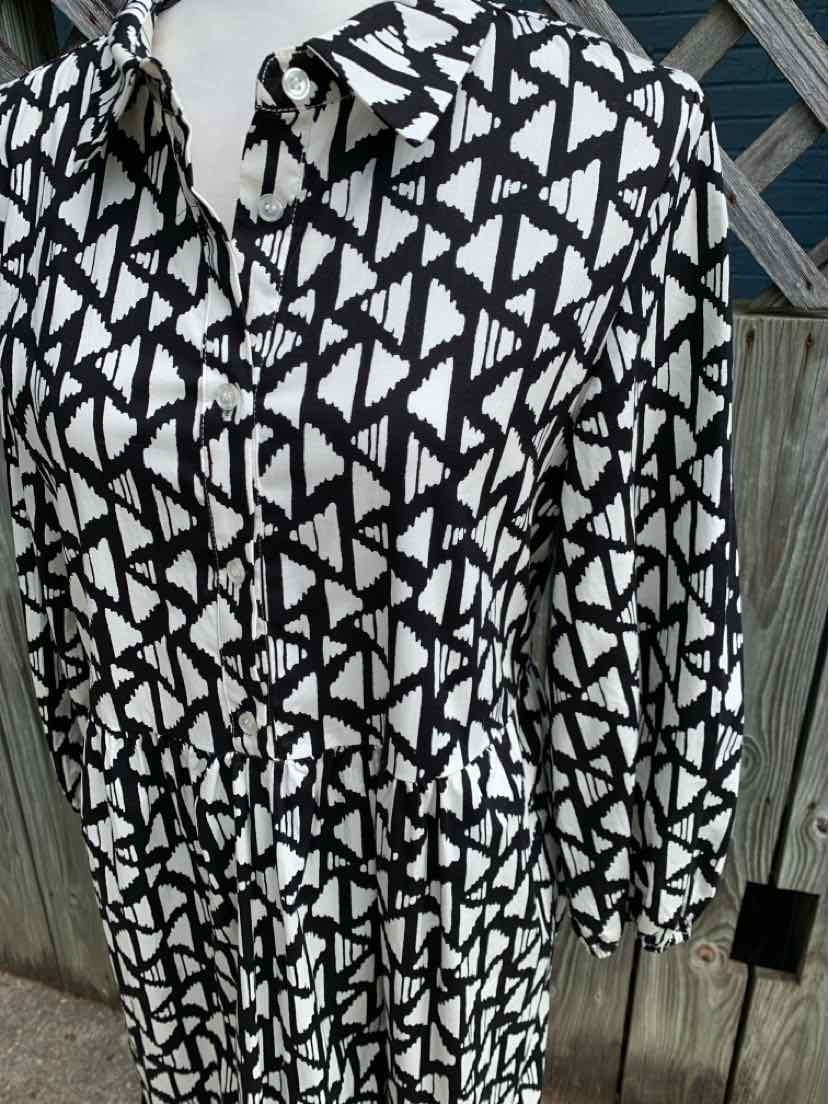 White blouse with black geometric triangle pattern, puffed long sleeves, and a gathered waist.