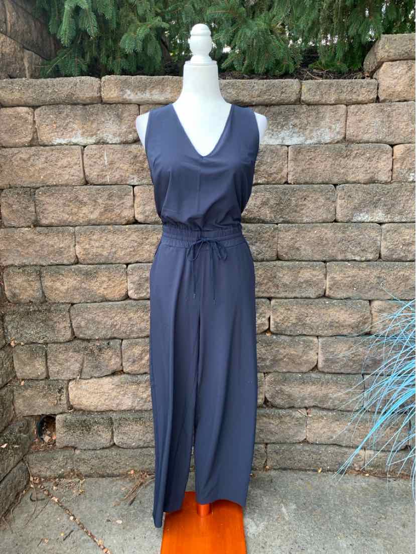 Sleeveless navy blue jumpsuit with V-neck and self-tie waist belt on mannequin.