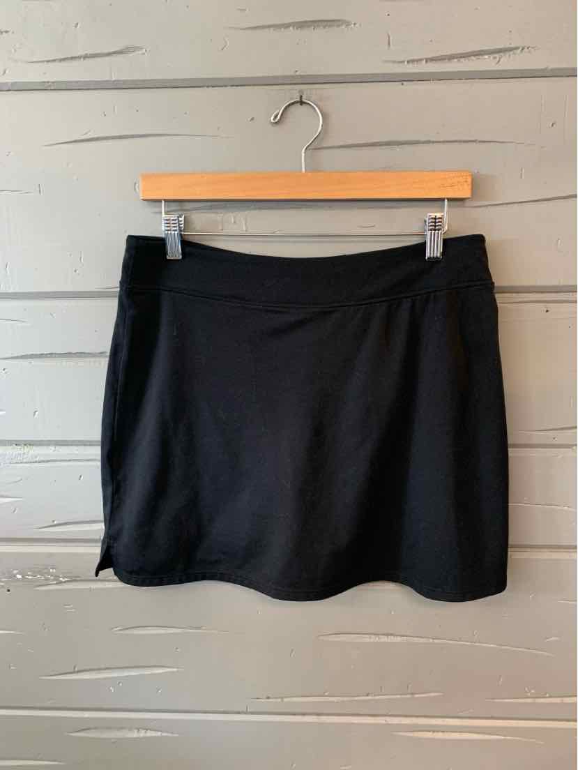 Black medium-length athletic skirt with smooth fabric and slight flare, hanging on wooden hanger.
