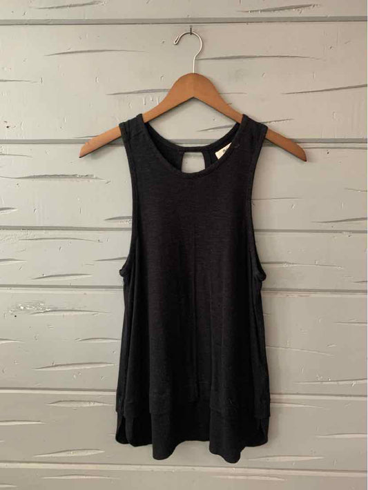 Black sleeveless ribbed tank top with crew neck and relaxed fit hanging on wooden hanger.
