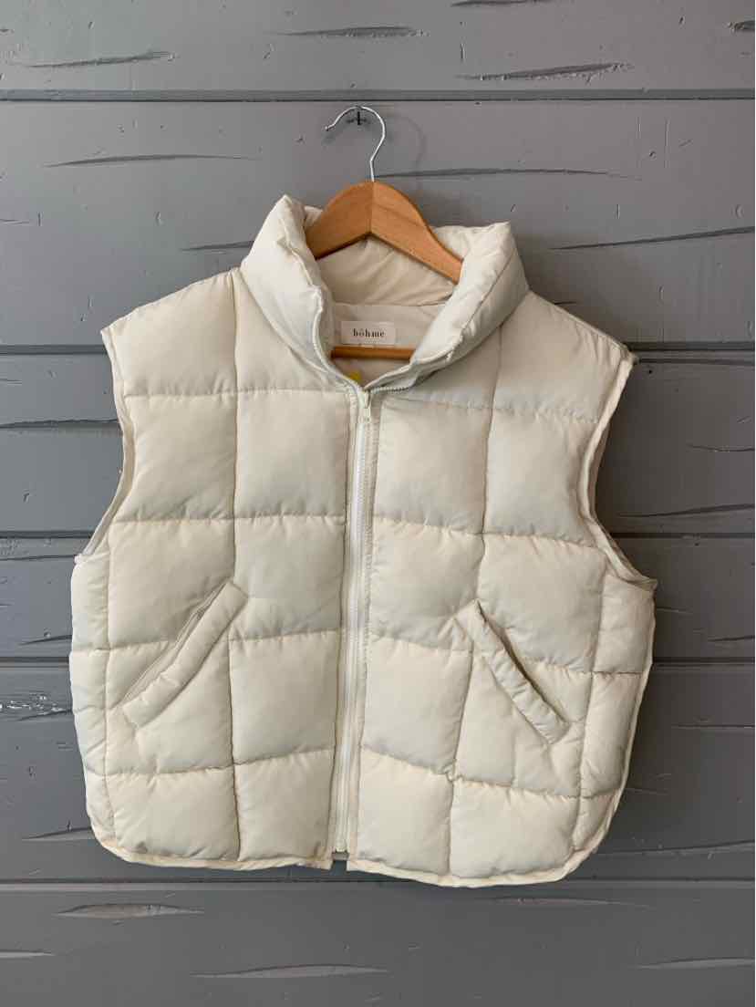 Cream-colored quilted sleeveless puffer vest with high collar and front pockets on wooden hanger.