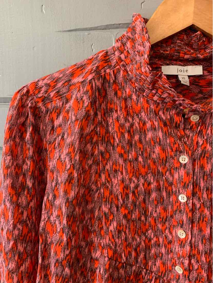 Red and black patterned blouse with ruffled high collar and white buttons in size XS.