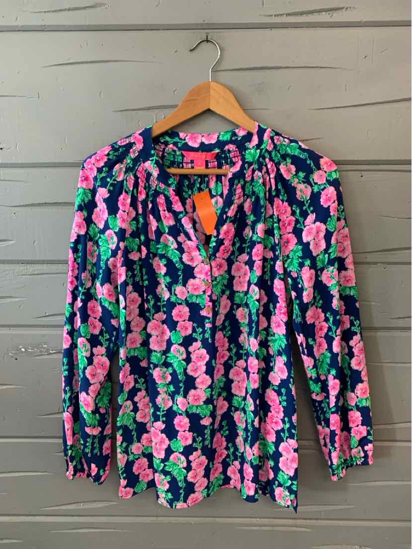 Long-sleeve blouse with vibrant pink and green floral print on navy background, lightweight fabric, V-neck with button.