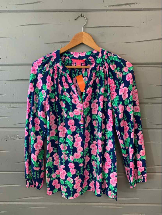 Long-sleeve blouse with vibrant pink and green floral print on navy background, lightweight fabric, V-neck with button.