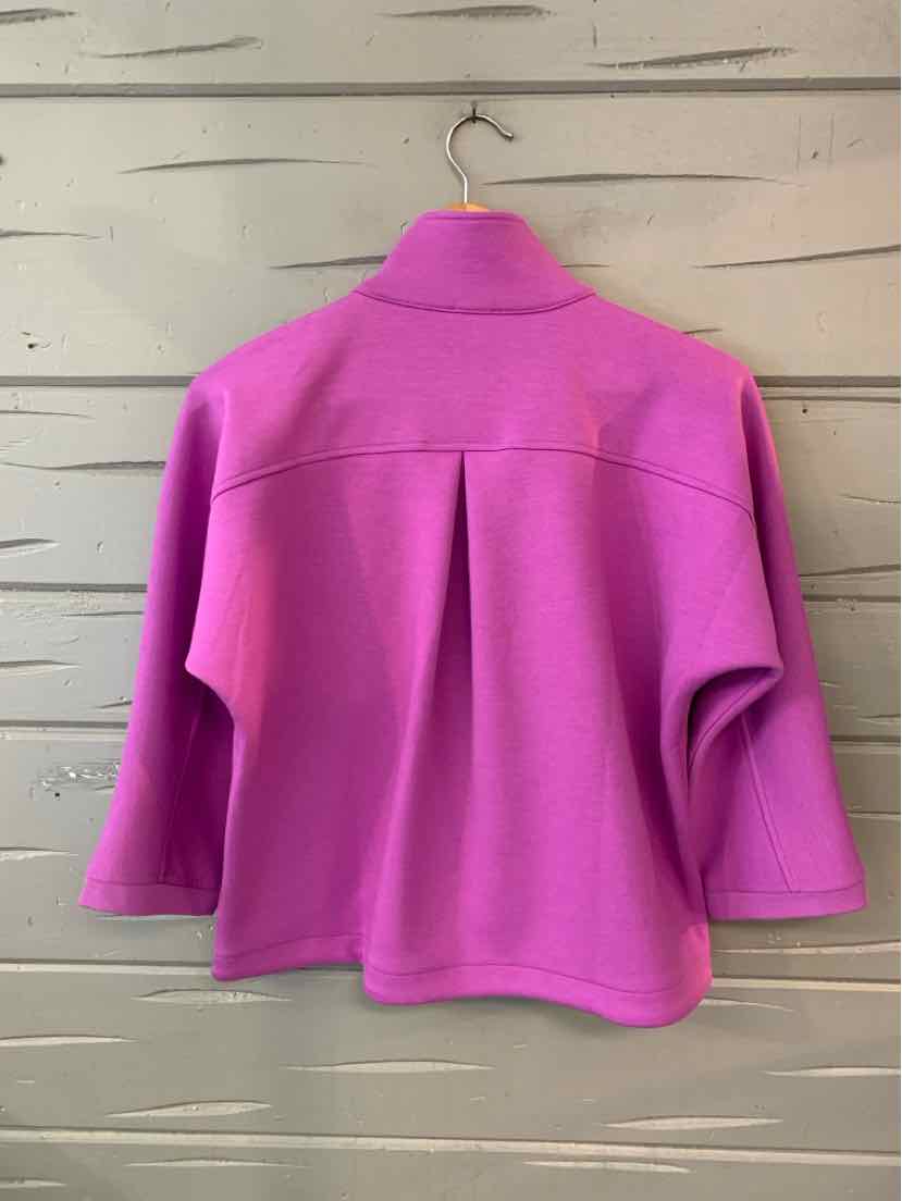 Bright pink wool blend jacket with wide collar, boxy fit, and three-quarter sleeves hanging on wooden wall.