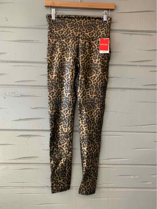 Leopard print high-waisted leggings with a red tag hanging, displayed on a wooden hanger against a textured gray wall.