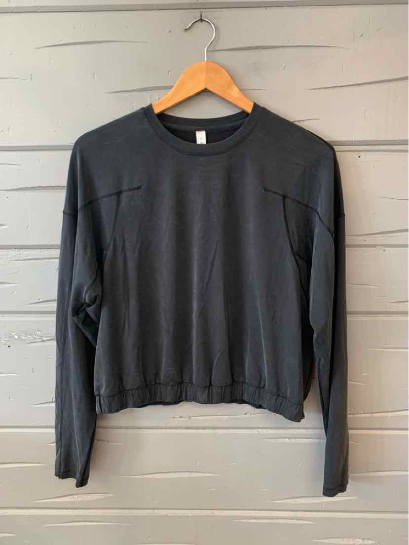 Black long-sleeve crewneck sweatshirt with relaxed fit and ribbed hem hanging on wooden hanger.