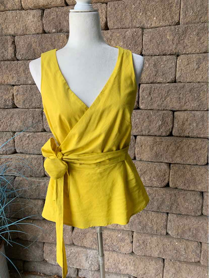 Sleeveless yellow wrap top with V-neck and side tie waist in lightweight fabric.