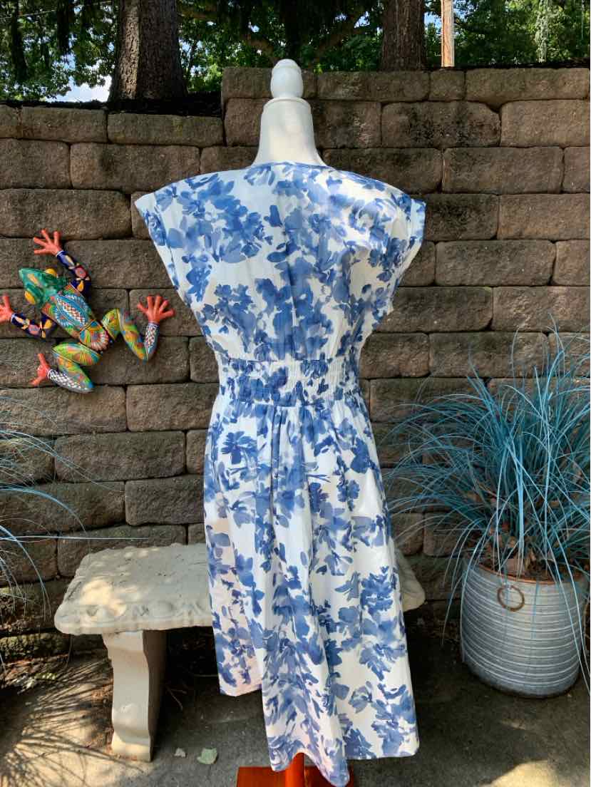 White midi dress with blue floral print, short sleeves, cinched waist, and flowy skirt.