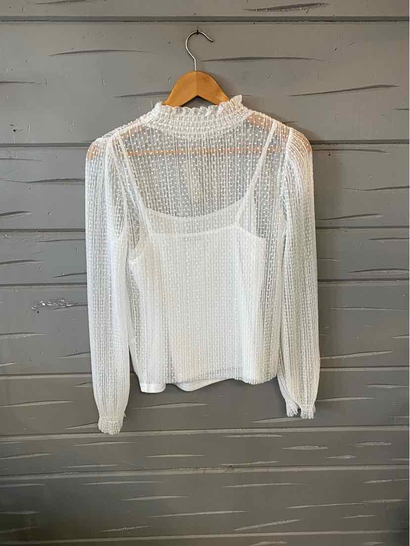 White lace long-sleeve blouse with sheer textured fabric and high neckline on wooden hanger.