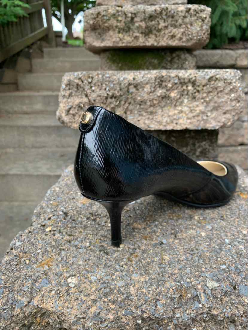 Black patent leather women's pump with pointed toe and mid-height stiletto heel.
