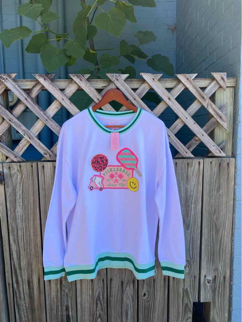White long-sleeve sweatshirt with green striped cuffs and hem, featuring colorful fruit and text graphic on front.
