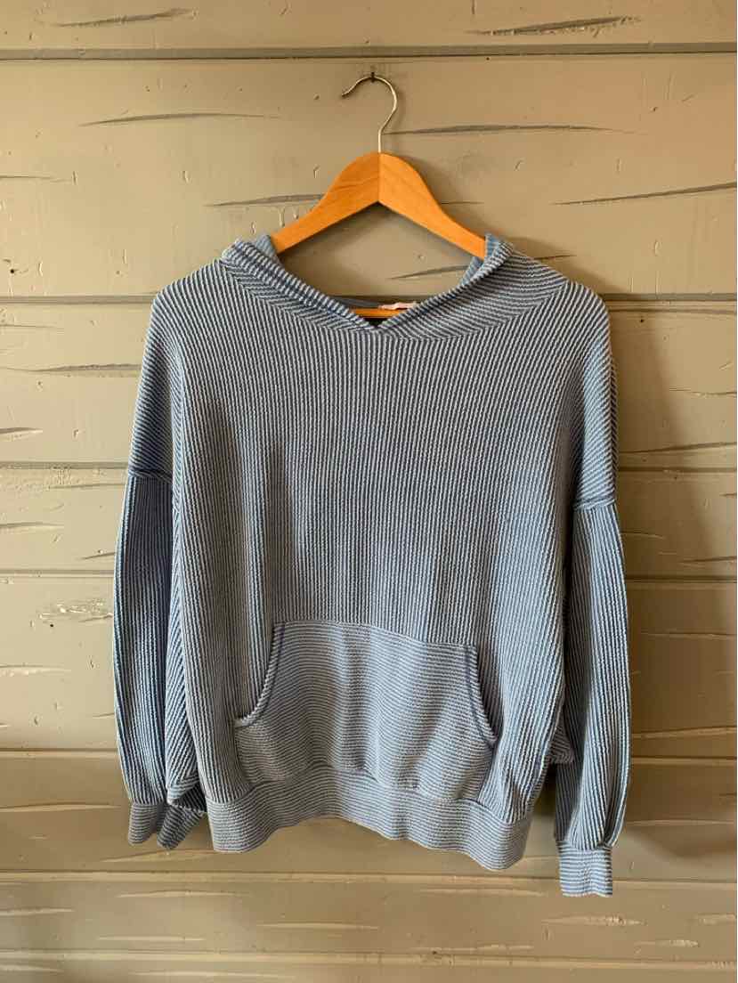 Light blue medium-size hoodie with front kangaroo pocket and ribbed cuffs hanging on wooden hanger.