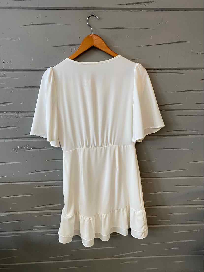 White short-sleeve dress with cinched waist and ruffled hem, hanging on wooden hanger.
