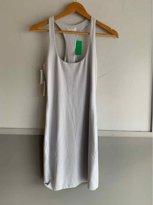 White sleeveless midi dress with scoop neckline on wooden hanger against plain wall.