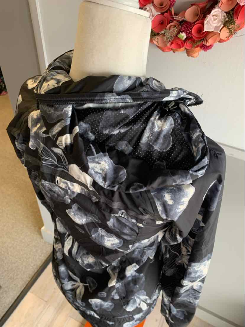 Black floral patterned lightweight jacket with gathered collar and long sleeves on mannequin.