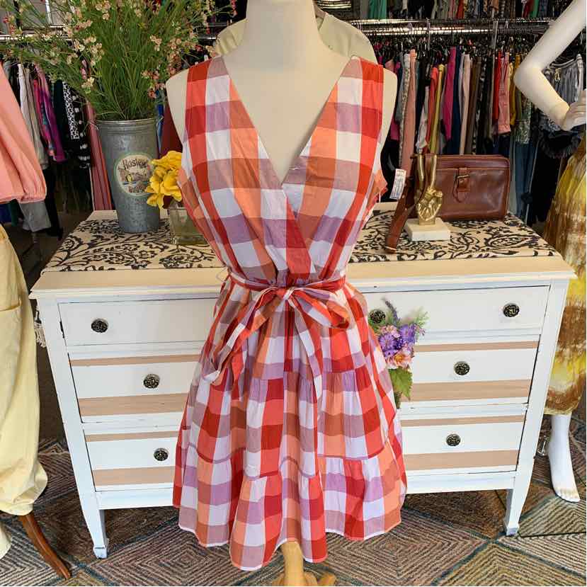 Sleeveless orange and white plaid dress with V-neck and waist tie on mannequin.