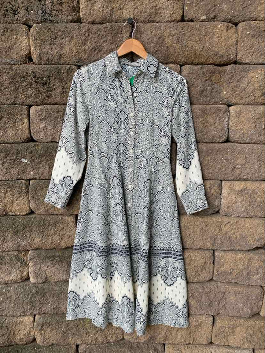Long-sleeve midi dress with gray and white intricate paisley and geometric patterns, button-up front, collared neckline.