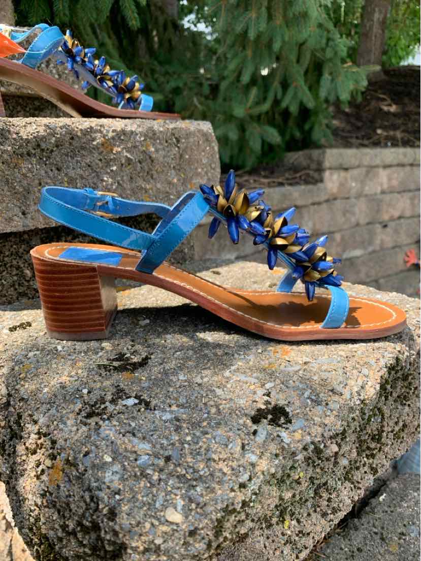 Blue leather open-toe sandal with wooden block heel and floral embellishments on straps.