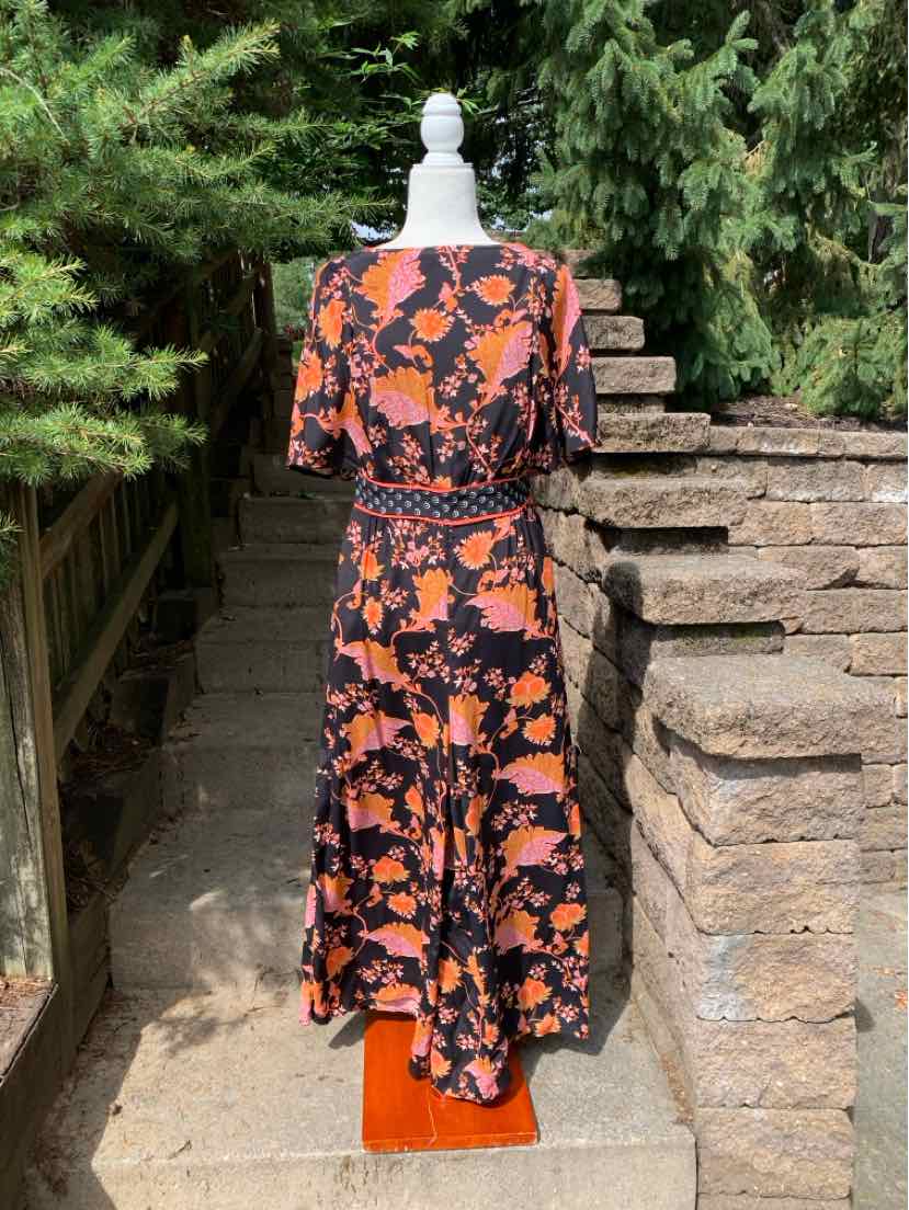 Black midi dress with orange floral print, short puff sleeves, and cinched waist belt.