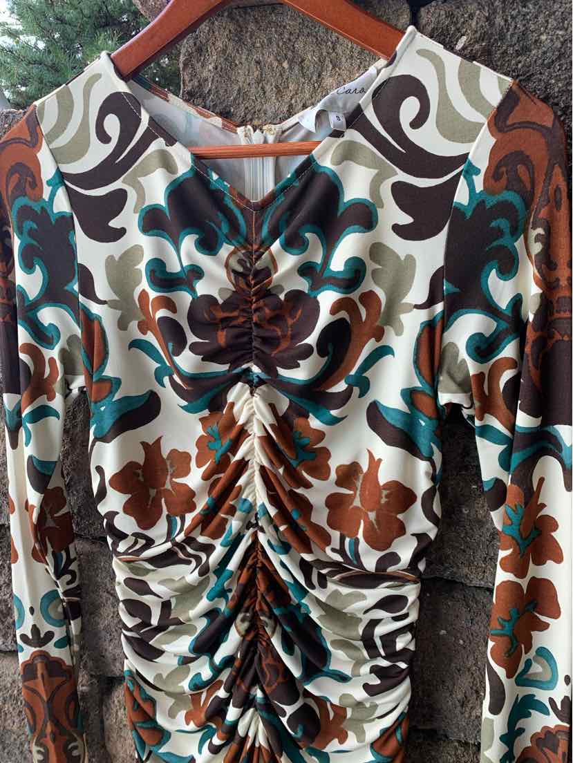 Multi-color floral print blouse with ruched center front and long sleeves on wooden hanger.
