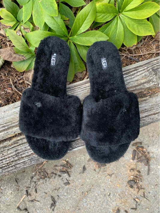 Black fuzzy open-toe slide sandals with thick sherpa straps and cushioned footbeds.