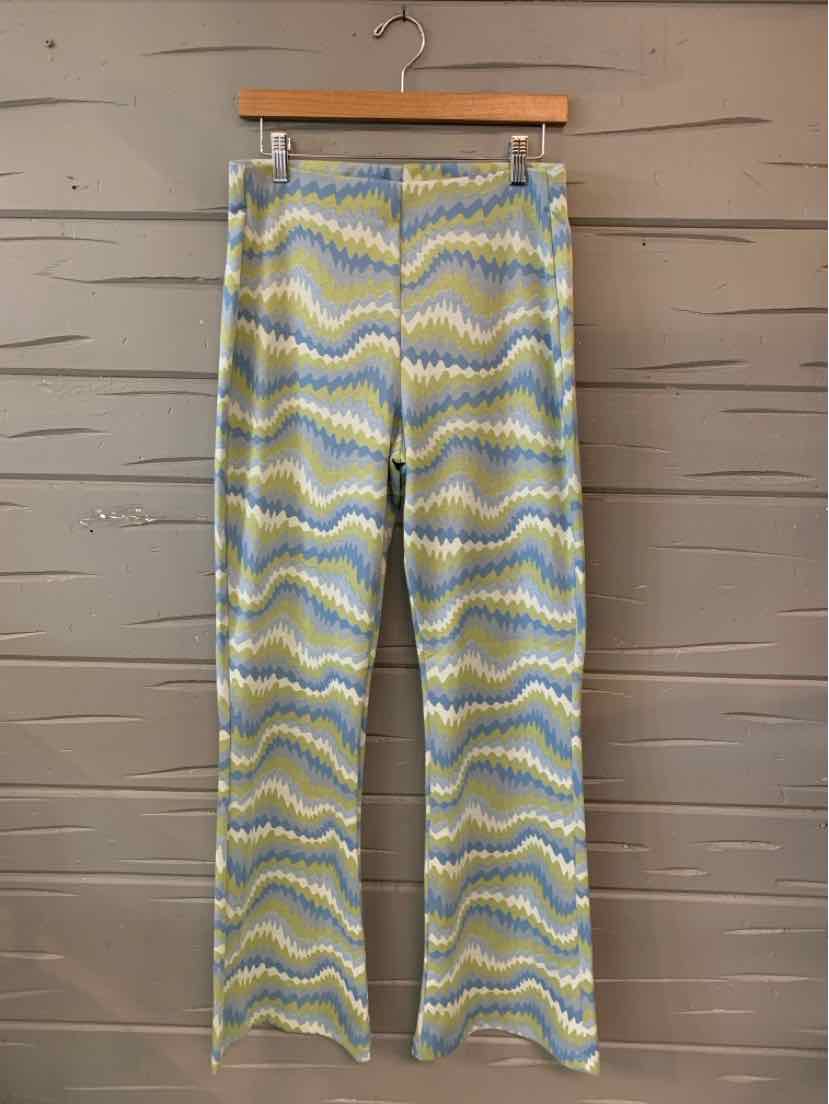 Light blue, yellow, and white wavy patterned wide-leg pants with a high waist and smooth fabric hanging on a wooden hanger.