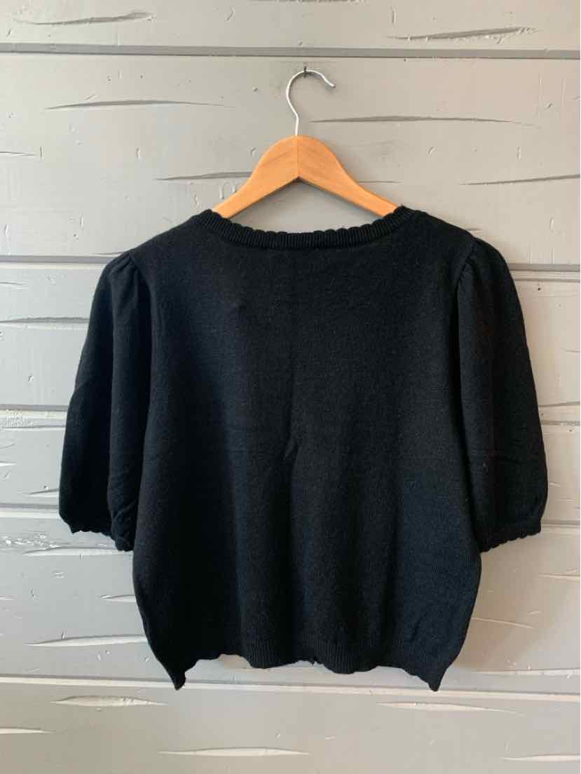 Black knit short-sleeve sweater with puffed sleeves and a round neckline on wooden hanger.