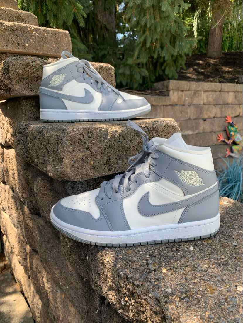 High-top Nike sneakers in light gray and white leather with a classic swoosh logo and cushioned sole.